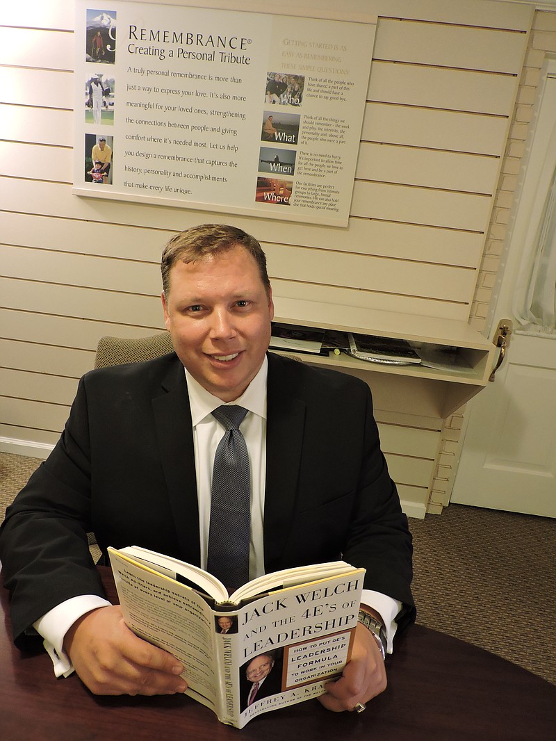 Lane Funeral Home South Crest Chapel managing partner Jason Cox showcases the book "Jack Welch and the 4-E's of Leadership" that helped him achieve the 4-E Leadership Award recently in Houston, Texas.