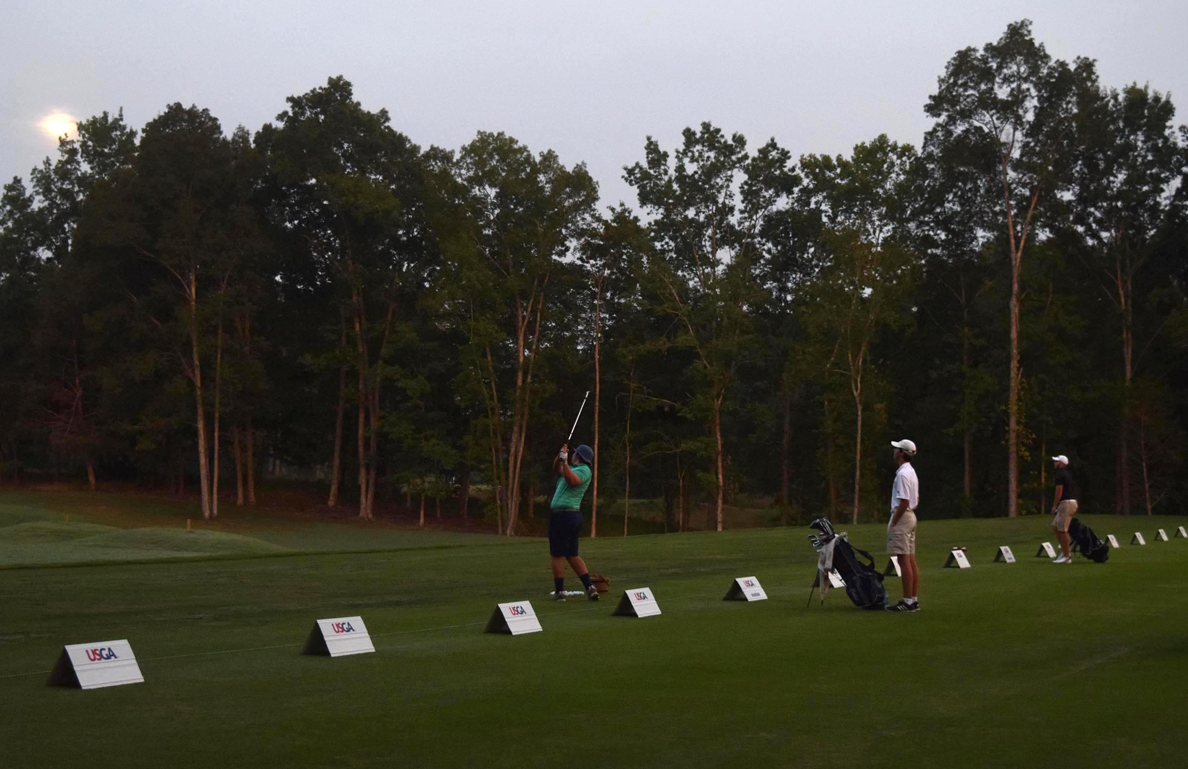 As the moon still lingers in the pre-dawn sky Brendan Hansen of Spring Lake, New Jersey hits the first shots off the practice tee. The third day of the 69th U.S. Junior Amateur Championship was held at the Honors Course in Ooltewah, Tennessee, Wednesday July 20, 2016.