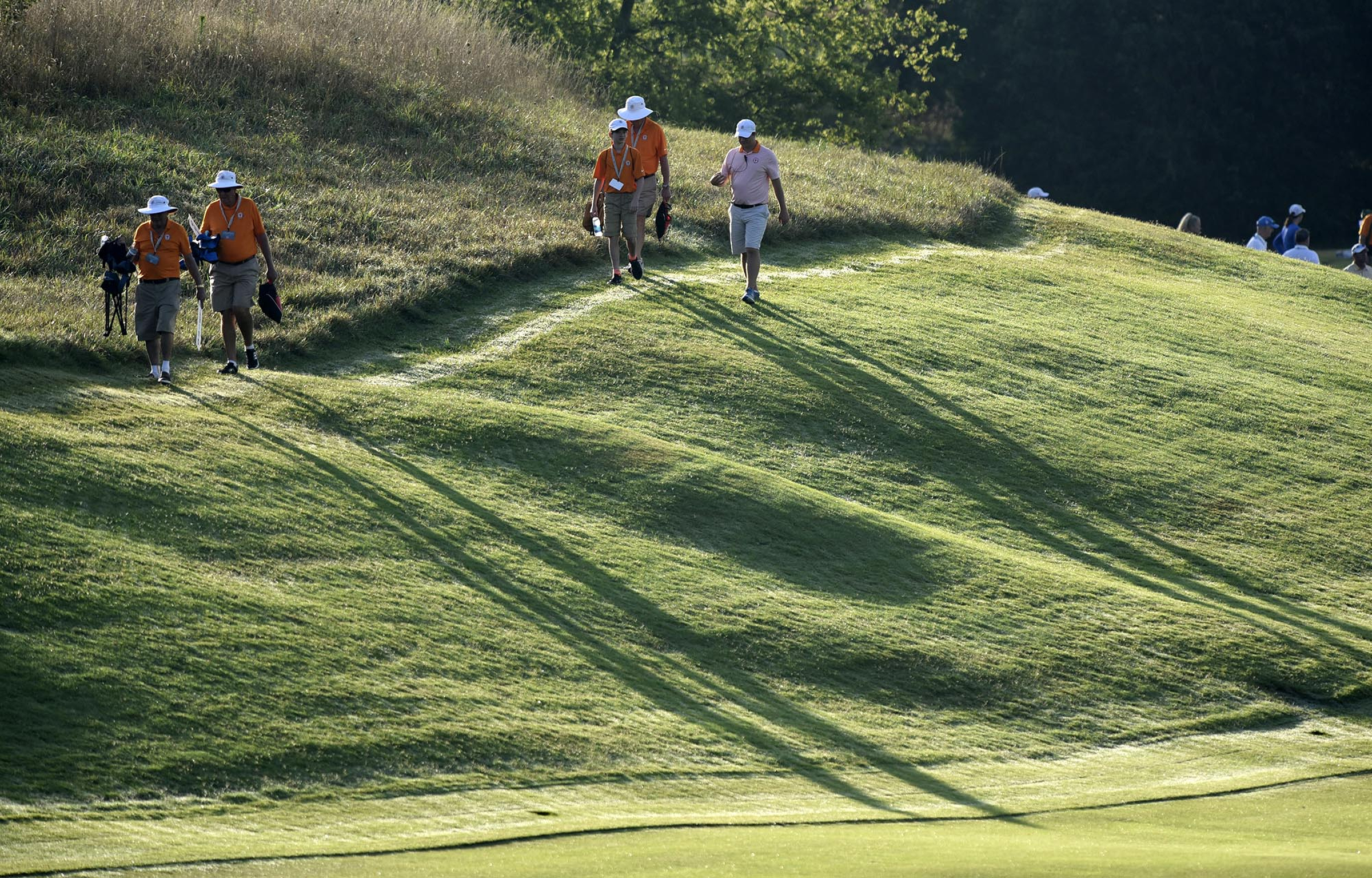 Volunteers cast shadows across the 11th hole as they head to their spots in the morning. The third day of the 69th U.S. Junior Amateur Championship was held at the Honors Course in Ooltewah, Tennessee, Wednesday July 20, 2016.