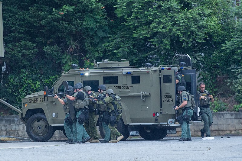 SWAT team members prepare to enter the Deercreek Gun Shop while searching for a person involved in a break-in, Tuesday, July 19, 2016, in Marietta, Ga. A gunman inside a gun shop near Atlanta began shooting at police officers, who returned fire after responding to reports of a break-in at the business shortly before dawn Tuesday, Marietta police said. Marietta police Officer Brittany Wallace said no injuries were reported and four suspects have been apprehended.