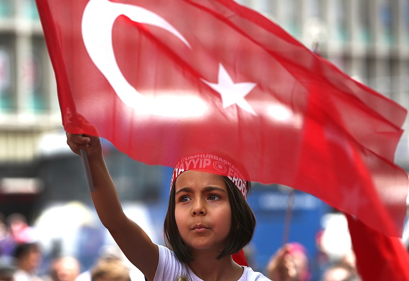 A Turkish girl wearing a headband bearing the name of Turkish president Recep Tayyip Erdogan waves her nation flags during a pro-government demonstration in front of the old parliament building, in Ankara, Turkey, Wednesday, July 20, 2016. The coup has led to public anger and calls for the government to reinstate capital punishment, while the state-run religious affairs body declared no religious rites would be performed for the coup plotters killed in the uprising.