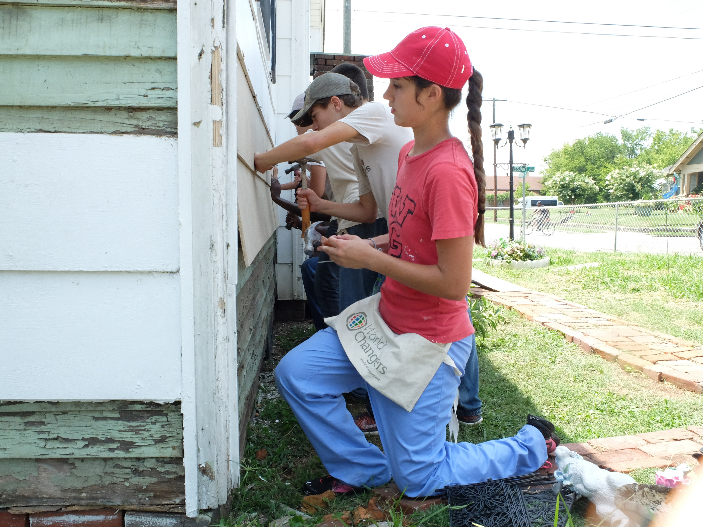 Megan Sherwin of Celeste, Texas, foreground, pauses to check her work as she and Luke Hawks nail new siding on an East Chattanooga house.