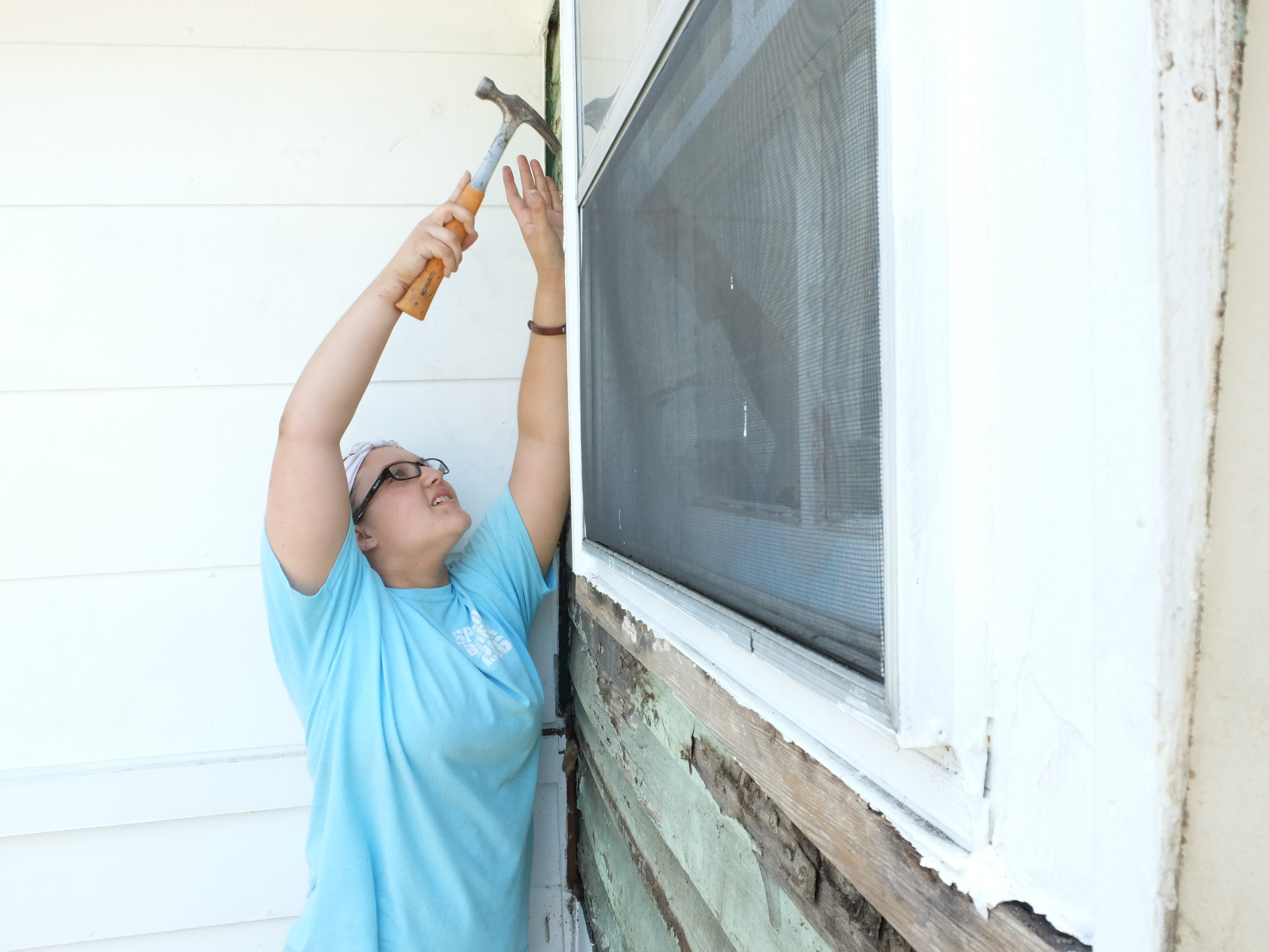 Mara Gibson, a 10th-grader from Hoboken, Ga., pulls nails from the exterior of an East Chattanooga house in preparation for new siding to be installed.