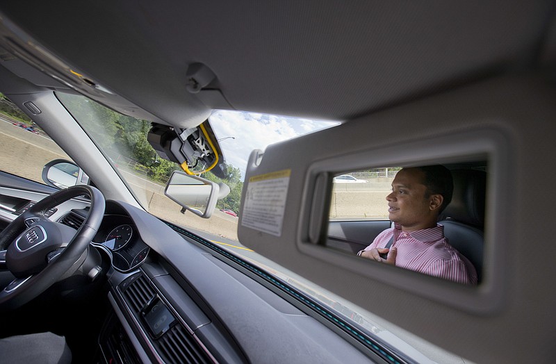 Kaushik Raghu, Senior Staff Engineer at Audi, is reflected in the passenger side visor mirror while demonstrating an Audi self driving vehicle on I-395 expressway in Arlington, Va., Friday, July 15, 2016. Experts say the development of self-driving cars over the coming decade depends on an unreliable assumption by most automakers: that the humans in them will be ready to step in and take control if the car's systems fail. Experience with automation in other modes of transportation suggests that strategy will lead to more deaths like that of a Florida Tesla driver in May. (AP Photo/Pablo Martinez Monsivais)