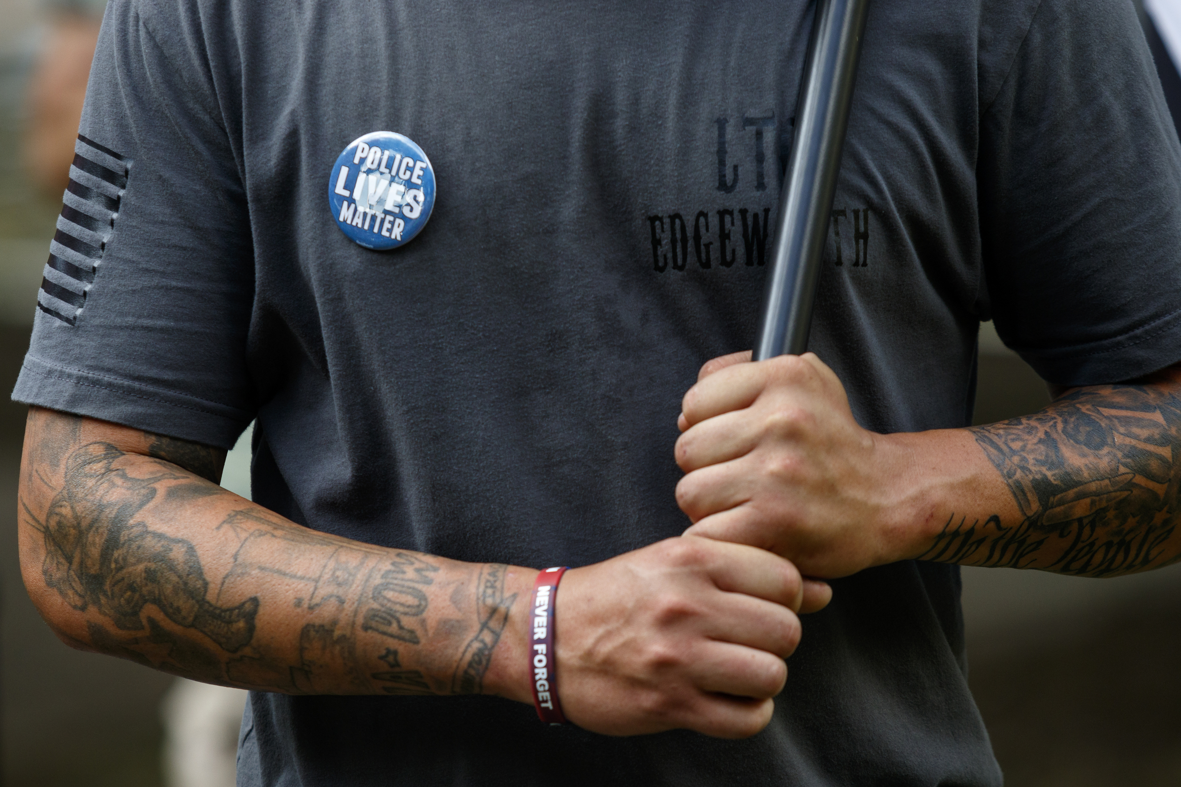 Matt Edgeworth with the State of Tennessee 3% group holds an American Flag and wears a "Police Lives Matter" pin near a Black Lives Matter protest in Miller Park on Thursday, July 21, 2016, in Chattanooga, Tenn. The State of Tennessee 3% group showed up to the protest to support both police and to offer water to protesters.