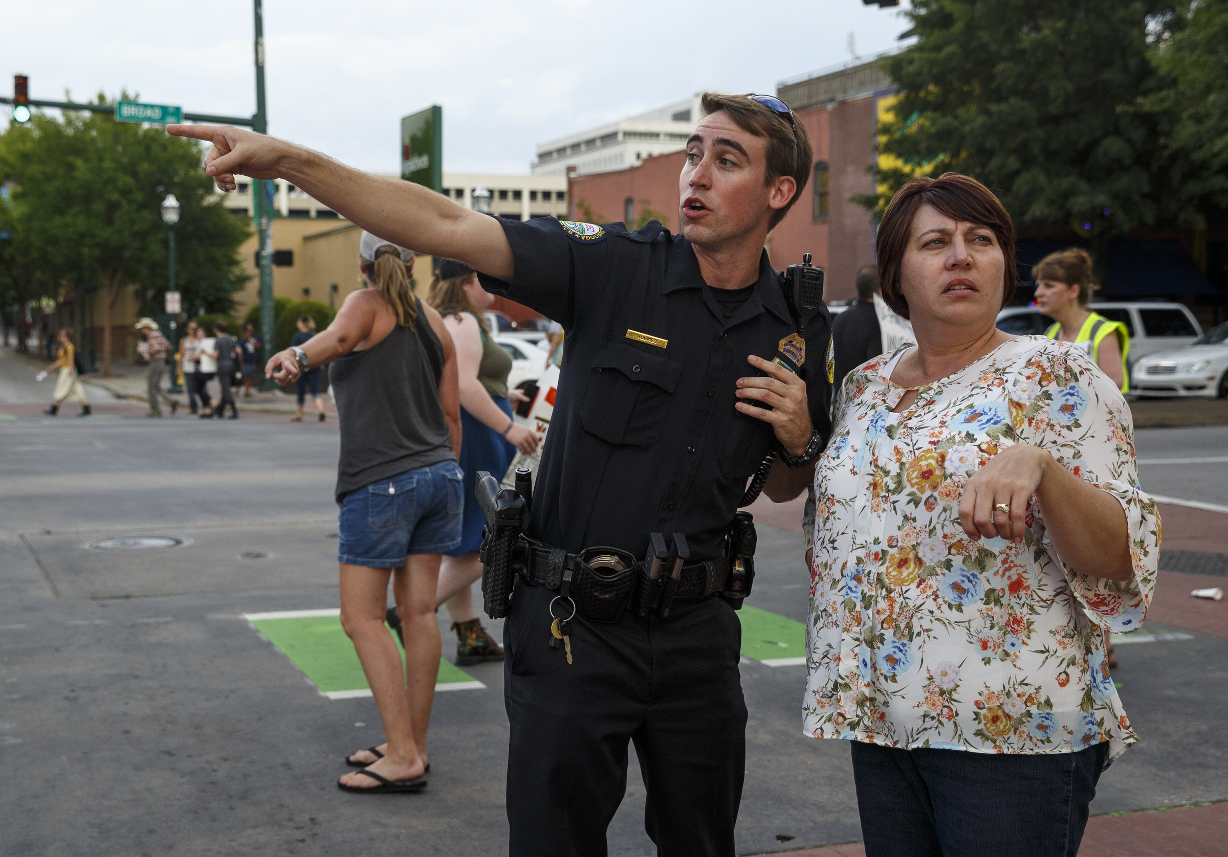 Chattanooga Police Officer Holmes, left, directs a woman on an alternate route to Erlanger Hospital after her vehicle was stopped when protesters shut down the intersection of Broad Street and 3rd Street during a Black Lives Matter protest Thursday, July 21, 2016, in Chattanooga, Tenn. The woman said she was on her way to see a relative's newborn. Protesters marched from Miller Park to the Tennessee Aquarium and back, stopping and blocking numerous intersections along the route.