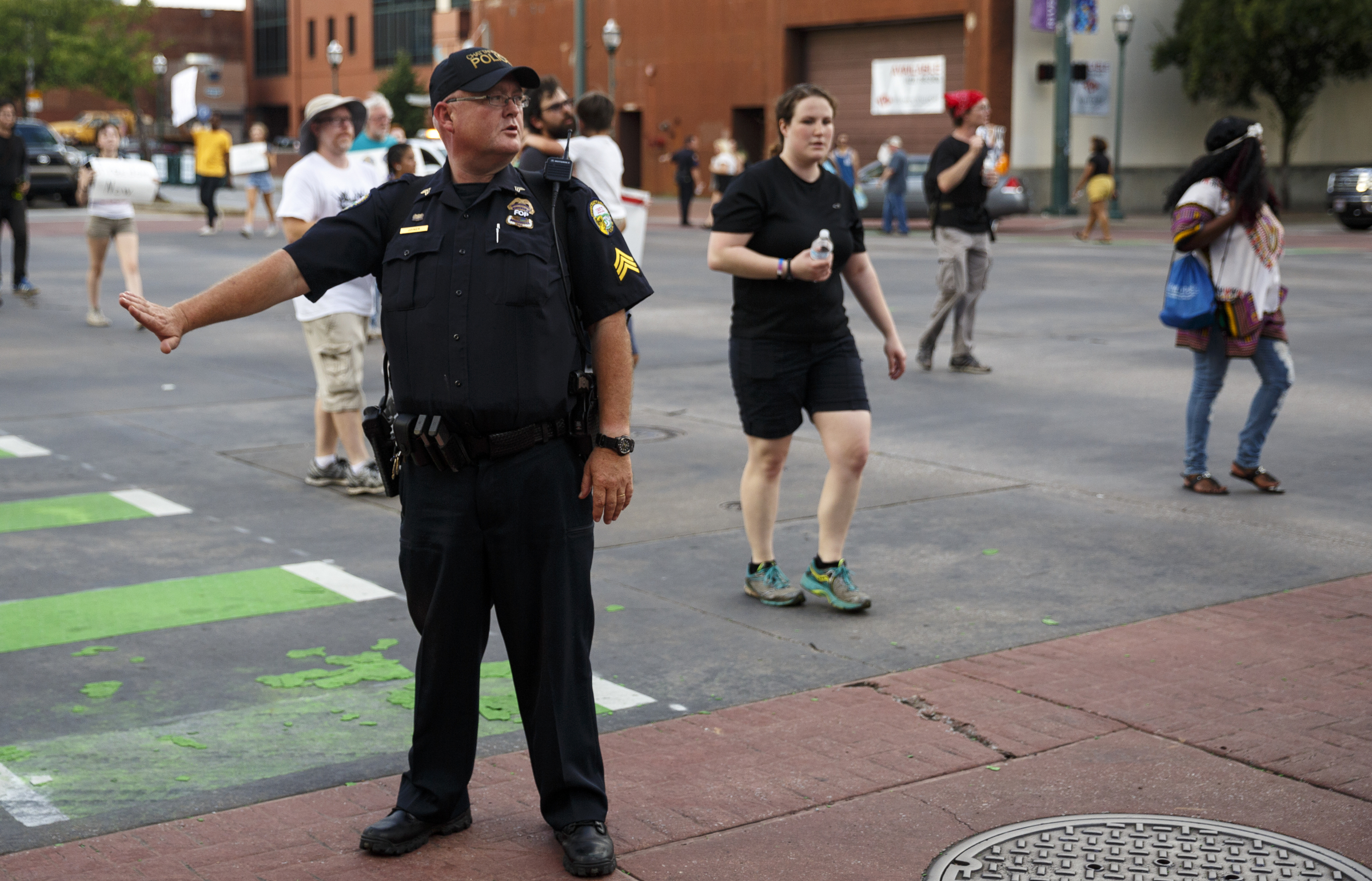 A Chattanooga Police Officer stops traffic for protesters blocking Broad Street and 3rd Street during a Black Lives Matter protest Thursday, July 21, 2016, in Chattanooga, Tenn. Protesters marched from Miller Park to the Tennessee Aquarium and back, stopping and blocking numerous intersections along the route.