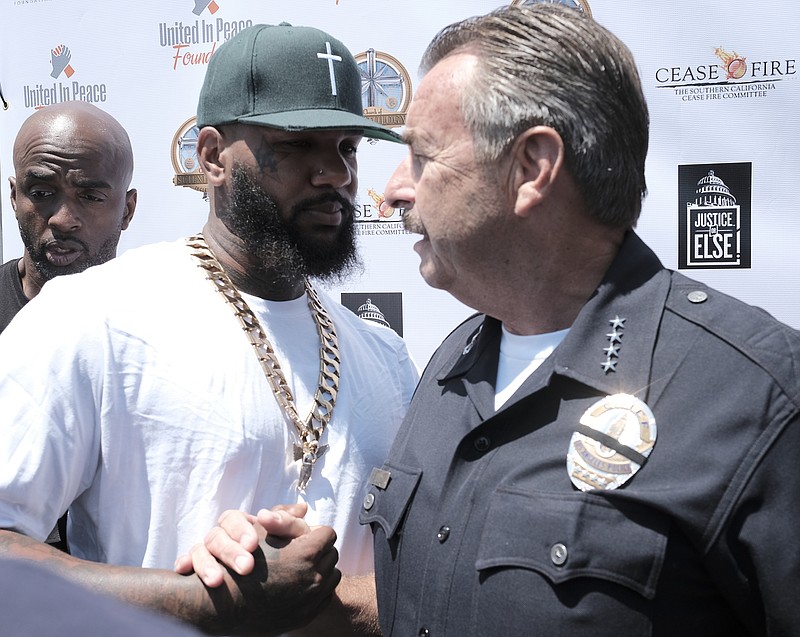 
              The Game, left, shakes hands with Los Angeles Police Chief Charlie Beck during "Time To Unite: United Hoods + Gangs Nation," a community summit organized by rappers The Game and Snoop Dogg, at the Church of Scientology Community Center in South Los Angeles with local gang members to discuss ways to curb violence, Sunday, July 17, 2016. The Game put the word out on social media, inviting leaders of the Crips, Bloods and other street gangs to come together at a town hall-style meeting. (AP Photo/Richard Vogel)
            