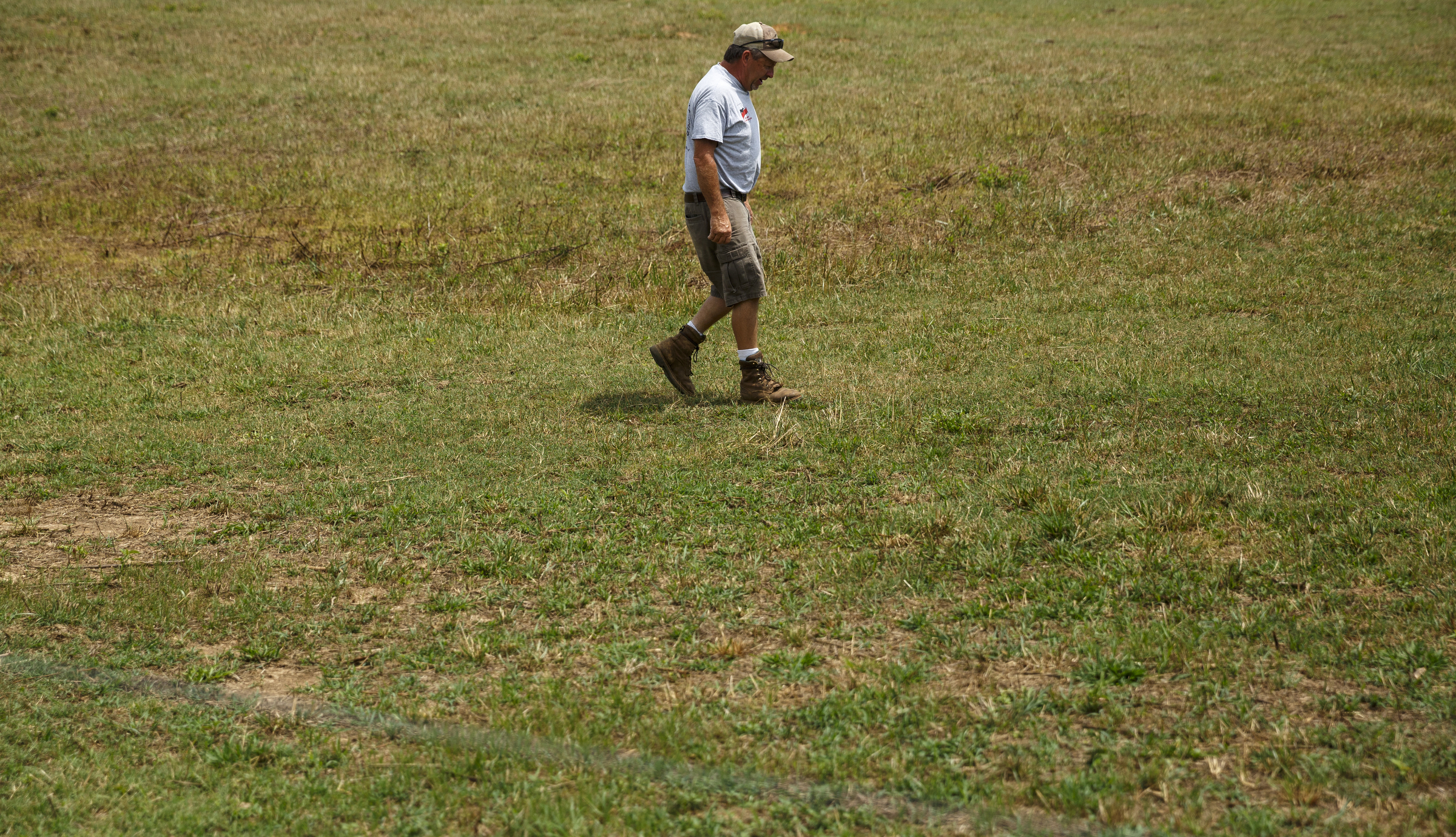 James Burton walks through a dry field on his farm on Thursday, July 21, 2016, in LaFayette, Ga. Burton says that the ongoing drought has forced him to graze cattle in fields he would normally save for next year, and while he would normally be selling his hay to customers, he has only just enough to last his own farm through the winter.