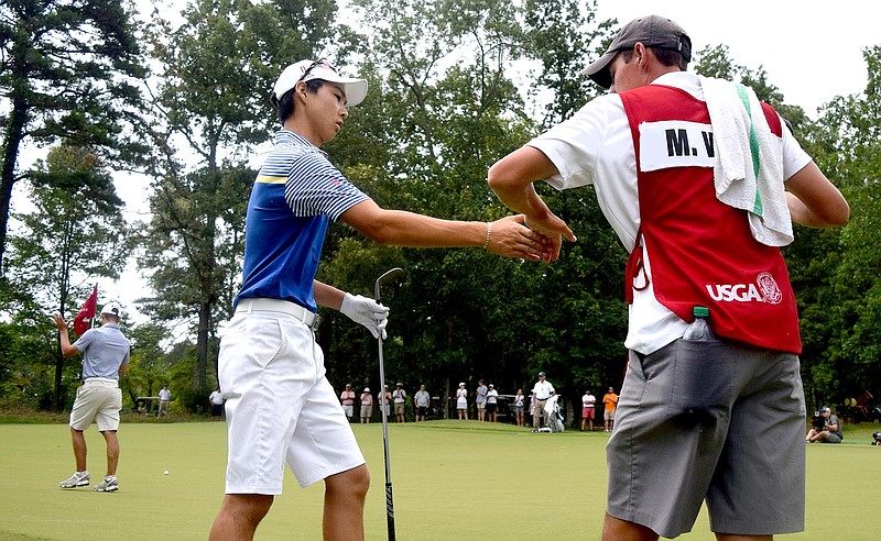 Australia's Min Woo Lee is congratulated by his caddie, Reid Smith, after a chip shot that landed 3 1/2 feet from the 35th hole.  In the background Lee's opponent, Noah Goodwin of Cornith, Texas claps.  The final day of the 69th U.S. Junior Amateur Championship was held at the Honors Course in Ooltewah, Tennessee, Saturday July 23, 2016. 
