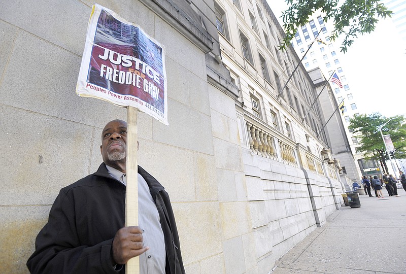 
              FILE- In this June 9, 2016 file photo, Arthur B. Johnson Jr., of Baltimore, demonstrates alone outside Baltimore's Courthouse East on the first day of the trial of Officer Caesar Goodson, one of six Baltimore city police officers charged in connection to the death of Freddie Gray, in Baltimore. More than a year after Freddie Gray's death, the same streets that exploded in fury and flame are calm. Despite back-to-back acquittals for officers charged in Gray's death, the physical protest movement that helped topple the careers of both the police commissioner and the mayor has dissipated, leaving activists exploring other avenues for change. (AP Photo/Steve Ruark, File)
            