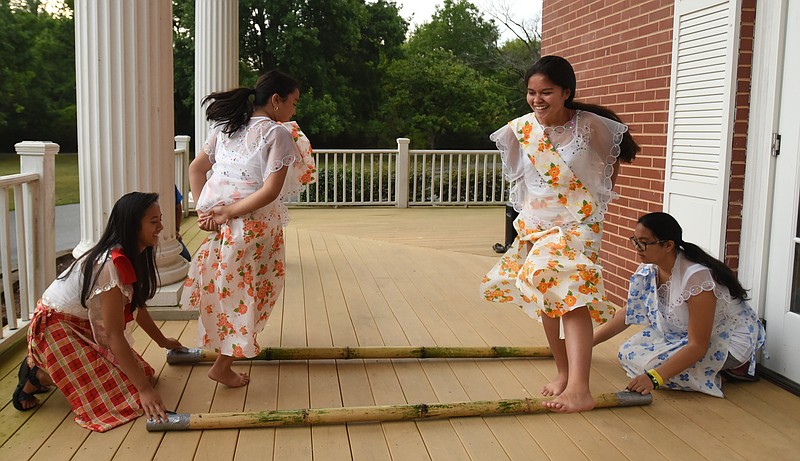 Juliana Gonzalez, left, and Ally Pendon slap sticks together as Becca Pendon, second from left, and Lexi Gowan demonstrate Tinikling, the national dance of the Philippines