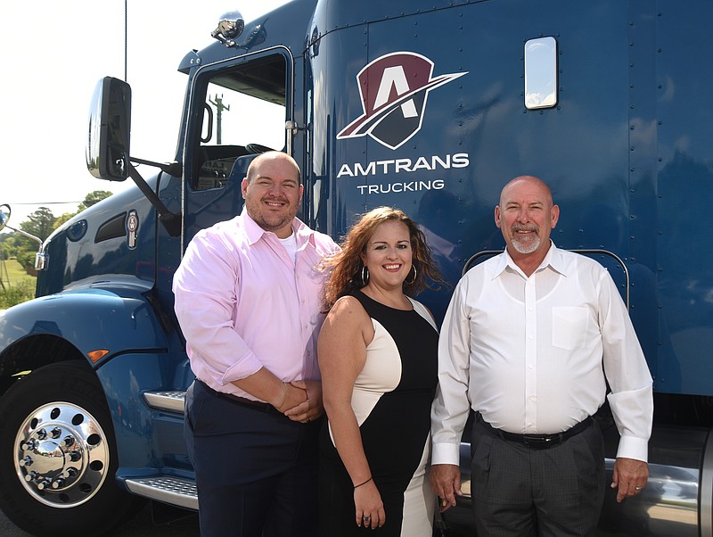 Anthony, Ashley and Stuart Wallace stand with an AmTrans USA truck.