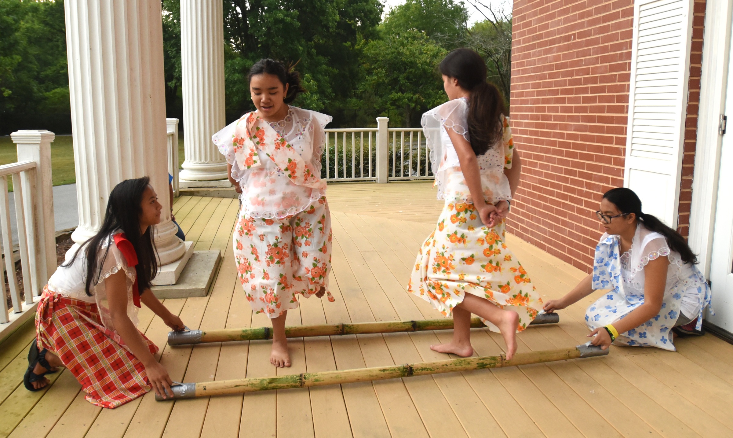 Juliana Gonzalez, left, and Ally Pendon, right, tap the sticks as Becca Pendon, second from left, and Lexi Gowan demonstrate Tinikling, the national dance of the Philippines, Monday, June 27, 2016 at Heritage Park.