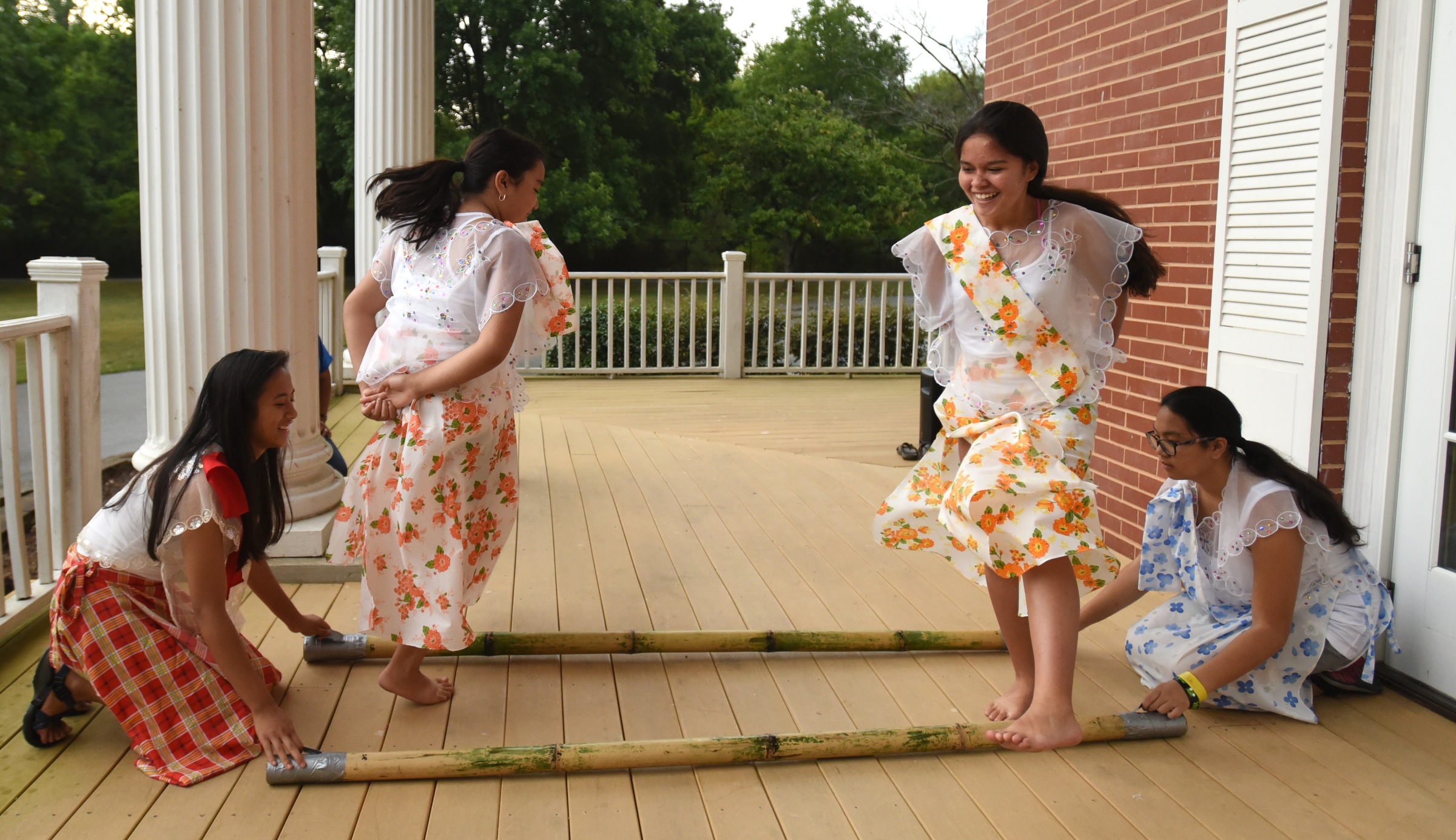 Juliana Gonzalez, left, and Ally Pendon, right, tap the sticks as Becca Pendon, second from left, and Lexi Gowan demonstrate Tinikling, the national dance of the Philippines, Monday, June 27, 2016 at Heritage Park.
