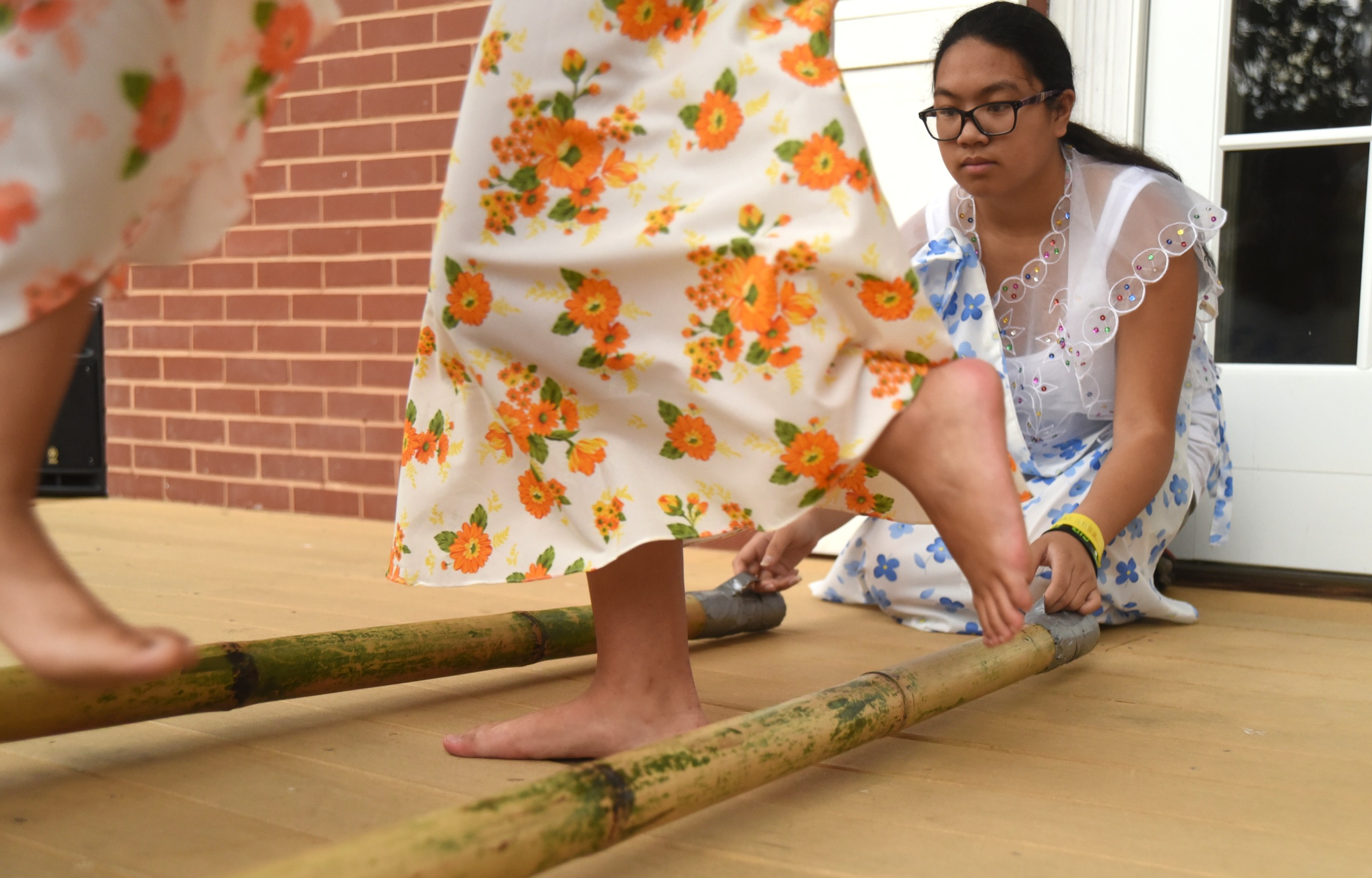 Lexi Gowan hops through the sticks, held by Ally Pendon, while demonstrating Tinikling, the national dance of the Philippines, Monday, June 27, 2016 at Heritage Park.