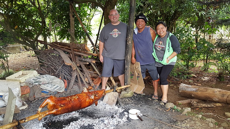 Jason Jones, left, his wife Annalyn and friend Rene Makiling roast a lechon (aka pig) over coals while on vacation in the Philippines. Once the lechon organs are removed, it is stuffed with onions, lemongrass and other treats, then sewn up. And the pig must be free-range, not factory-raised.