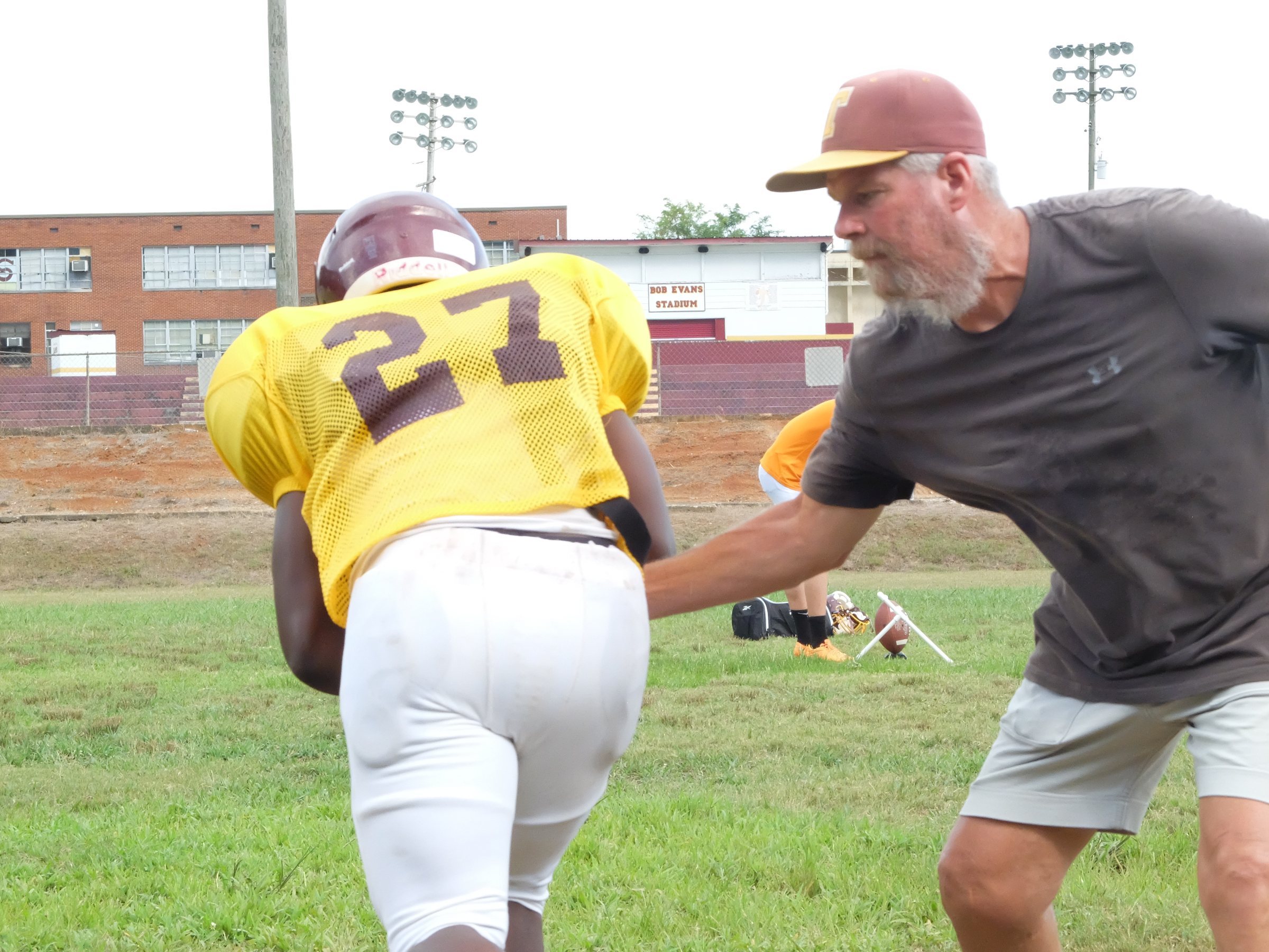 Tyner's Tyone Young (27) takes the hand off from Coach Wayne Turner during practice on Monday.
