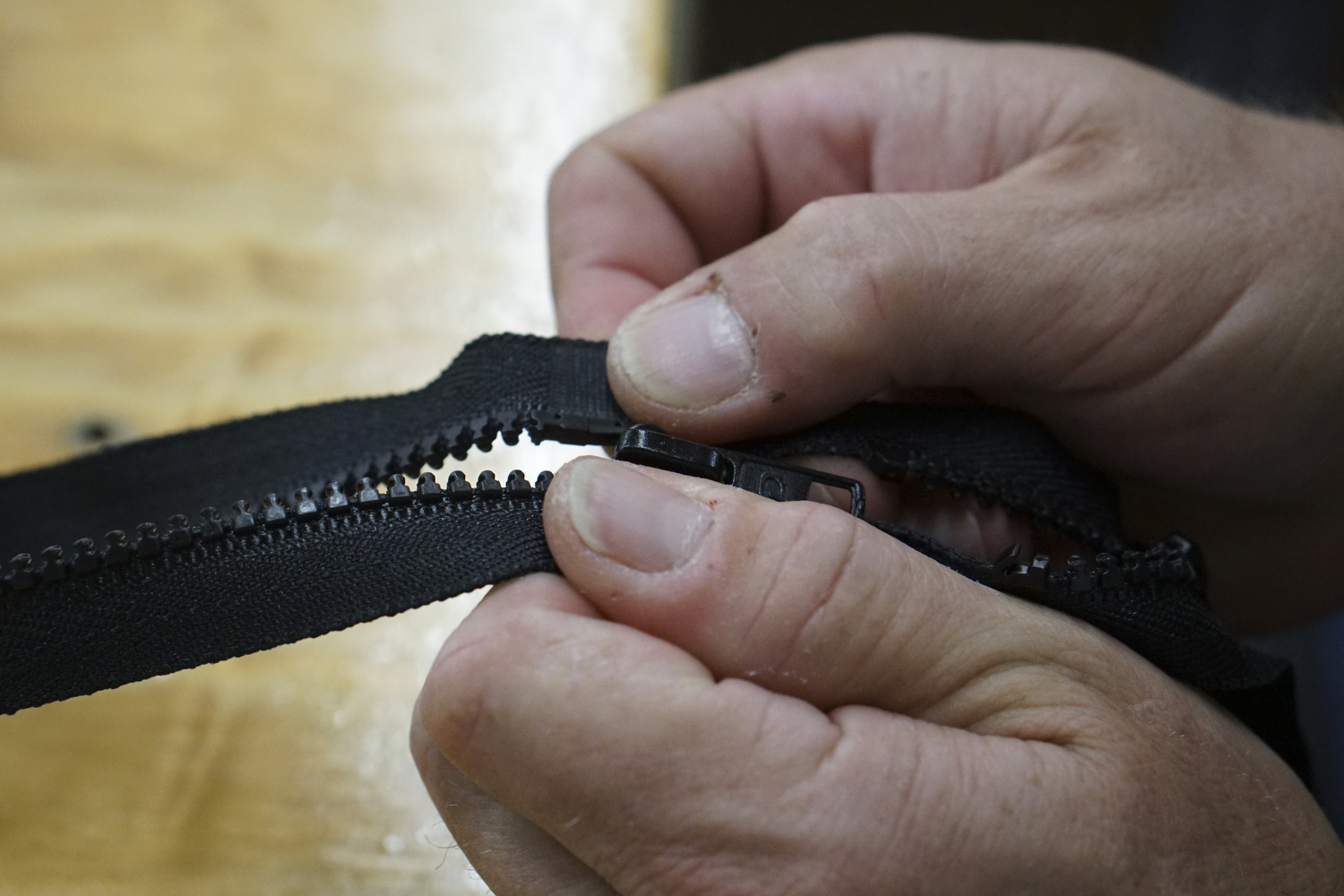 Staff Photo by Dan Henry / The Chattanooga Times Free Press- 7/25/16. John Pascoe adds sliders to molded zippers while at Dunlap Industries on Monday, July 25, 2016. DI makes molded and coil zippers for use with U.S. Army and other high use applications.