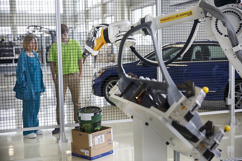 Mechatronics student Cameron Newman, right, and Teresa White watch as another student operates a training robot at the Volkswagen manufacturing plant on Thursday, June 16, 2016, in Chattanooga, Tenn. This fall, 27 Hamilton County high school juniors will enroll in Volkswagen's new Mechatronics Akademie where they will spend 2 years learning how to run and maintain industrial robots.