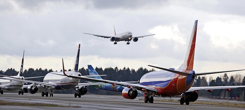 
              FILE - In this Dec. 16, 2015 file photo, a passenger jet comes in for a landing and in view of a line of planes waiting to takeoff, at Seattle-Tacoma International Airport.  U.S. environmental regulators are moving to limit emissions from aircraft, ruling that jet engine exhaust is endangering human health by warming the planet. The Environmental Protection Agency announced Monday that it will use its authority under the Clean Air Act to regulate aircraft emissions.  (AP Photo/Elaine Thompson)
            