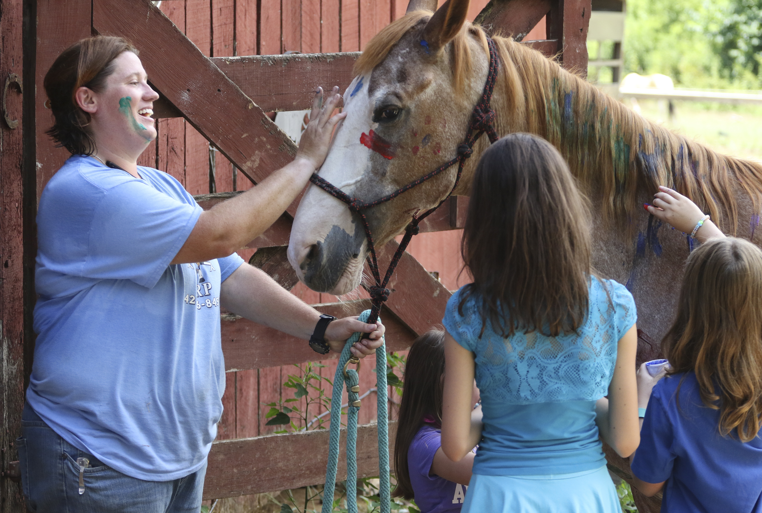Barn manager Amber Meadows, Erin Holder, 12, and Brooklyn Bernarding, 9, paint "Apollo" during the Highlands Riding Center summer camp.