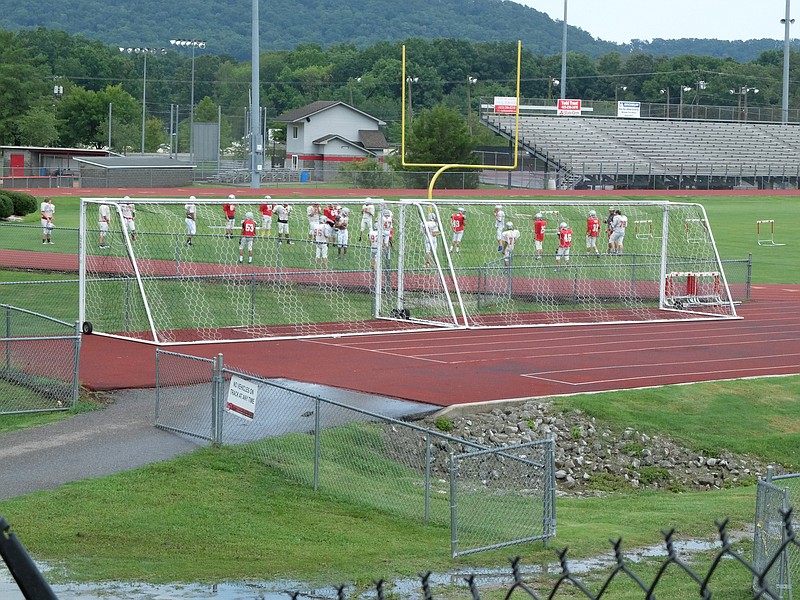 The Ooltewah High School football team practices on the football stadium field as soccer nets are set to the side.
