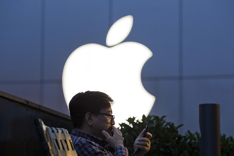 
              FILE - In this Friday, May 13, 2016, file photo, a man uses his mobile phone near an Apple store in Beijing. Apple reports financial results Tuesday, July 26, 2016. (AP Photo/Ng Han Guan, File)
            