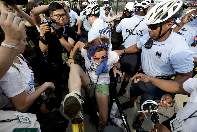 A demonstrator is taken into custody by police after climbing over a barricade near the AT&T Station, Monday, July 25, 2016, in Philadelphia, during the first day of the Democratic National Convention.