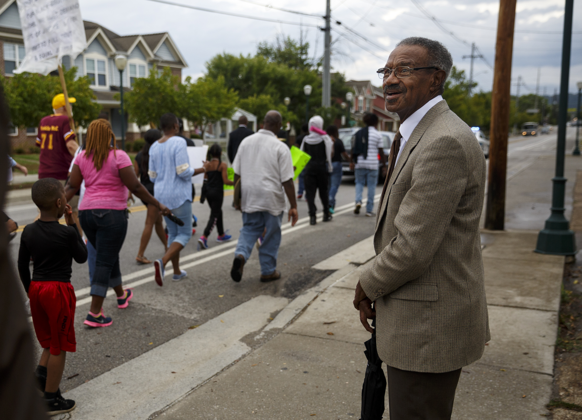 Ronald Dodds, Sr., watches as demonstrators march along East 38th Street from South Chattanooga Recreation Center to Westside Baptist Church before a town hall meeting at the church to discuss race relations and poverty Thursday, July 28, 2016, in Chattanooga, Tenn. A panel of speakers took part in a discussion about race, poverty, and policing.