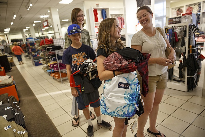 Christy Schmeck and her children Peyton, Nate, and Aidan, from right, wait in line to check out on the first day of tax-free weekend shopping at the J.C. Penney store Friday, July 29, 2016, in Chattanooga, Tenn. Items like clothing and backpacks are tax free for the weekend at Tennessee retailers.