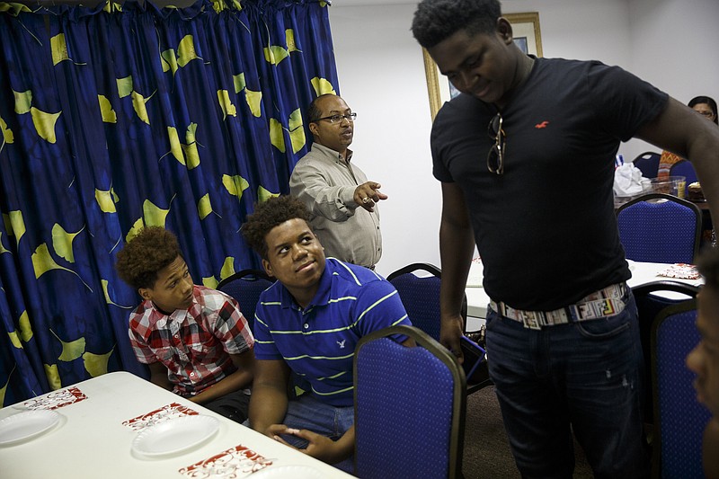 Oliver Richmond, center, points to Javontae Harris, right, as he talks with Harris, Devonte Wigfall, left, and Austin Lewis at a celebration luncheon for the men at Front Porch Alliance on Friday, July 29, 2016, in Chattanooga, Tenn. They were among 5 students who were paid $10 an hour over the summer to learn money management and lawn work.