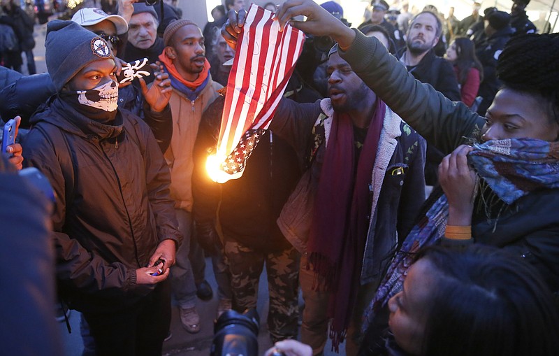 
              FILE - In this Feb. 23, 2016 file photo, protesters burn an American flag in Chicago. Champaign County Ill., State's Attorney Julia Rietz was alerted on July 4, 2016, that police had just arrested a resident on suspicion of burning an American flag. Rietz said she knew "immediately" that the Urbana Police Department needed to release him. The state law used to jail him, though clear in its prohibition of desecrating either the U.S. or state flags, is unconstitutional. (AP Photo/Charles Rex Arbogast, File)
            