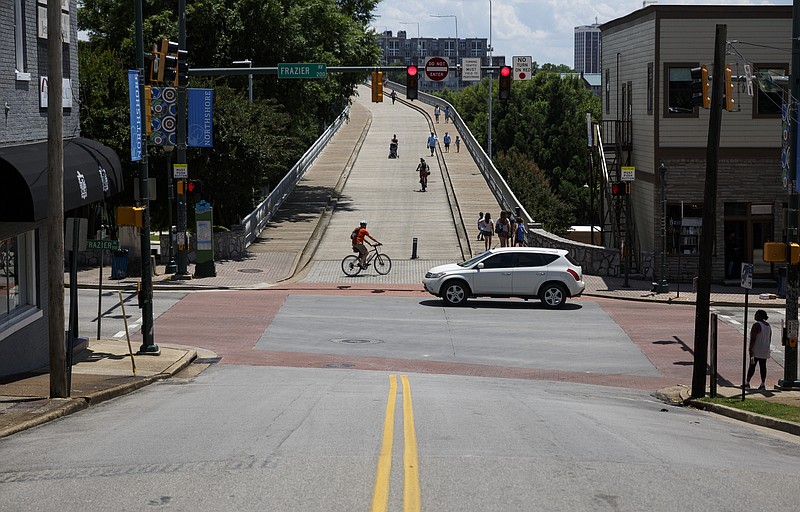 A vehicle travels on Frazier Avenue as a cyclist turns from the sidewalk onto the Walnut Street Bridge. A transportation design firm suggested the city temporarily stripe Frazier Avenue before going through with proposed bike lanes that would reduce the road to two lanes and a turn lane, but not even the test will be followed up on based on the number of concerns from area residents and businesses.