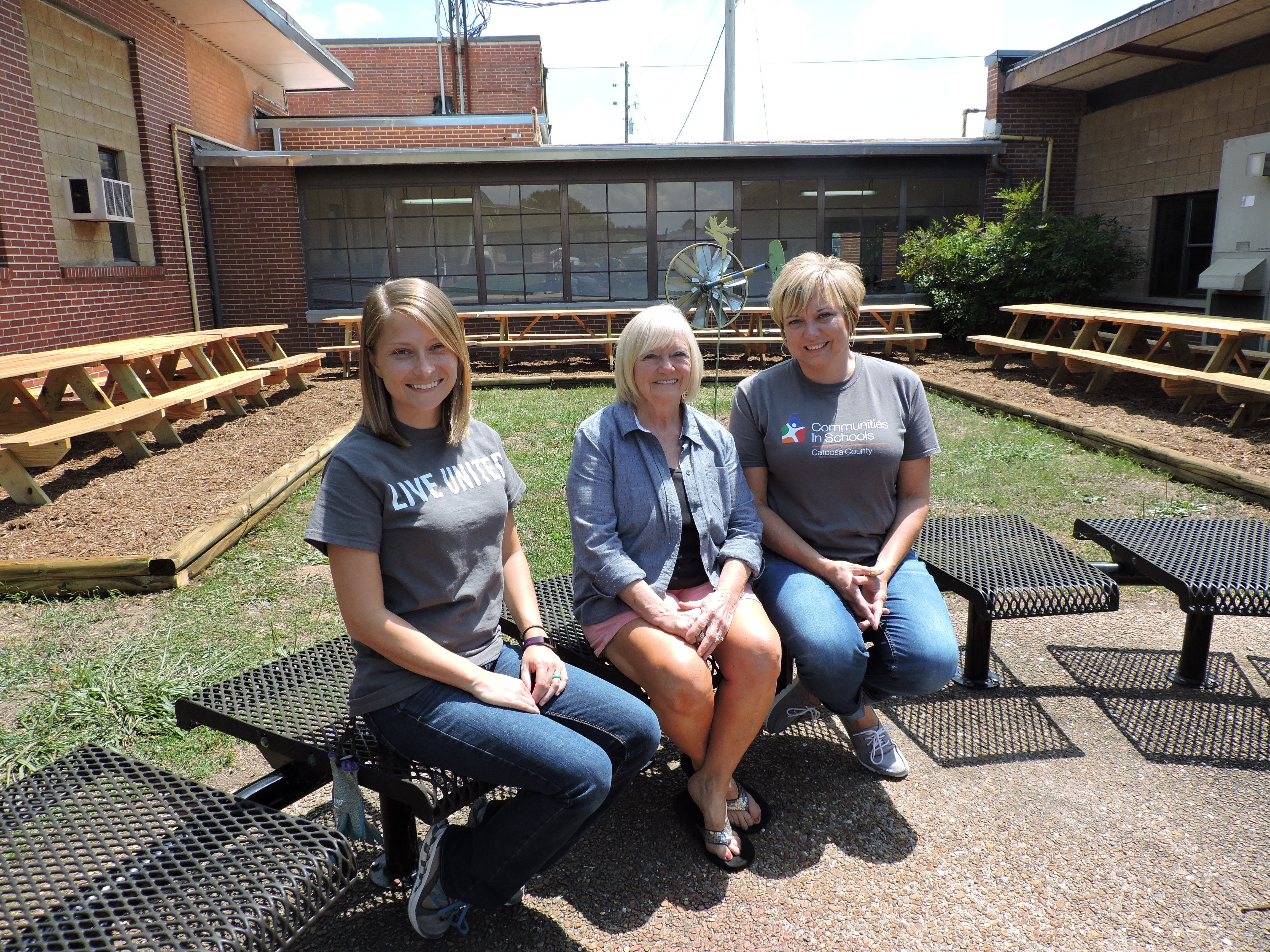 From left, Shaw process improvement engineer Laura Porter, Performance Learning Center Principal Sharon Vaughn and Communities in Schools Executive Director Suzanne Chovanec sit in the newly improved courtyard at the PLC.