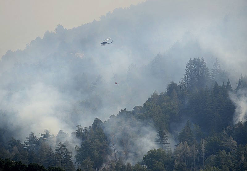 
              A helicopter flies in to make a water drop while fighting a wildfire on a ridge above Rancho San Carlos in Carmel Valley, Calif., Saturday July 30, 2016. Fire officials say a wildfire burning near California's dramatic Big Sur coast has destroyed dozens homes and is threatening over a 1,000 more. (David Royal/The Monterey County Herald via AP) MANDATORY CREDIT
            