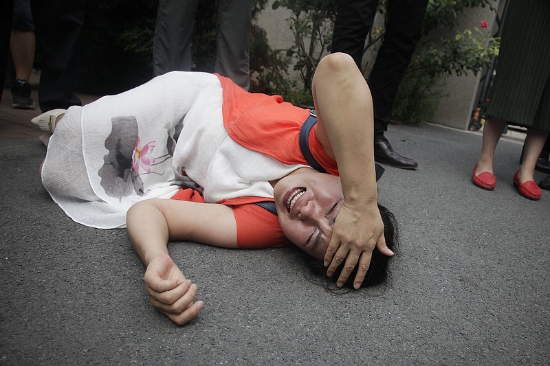 
              Fan Lili, the wife of imprisoned lawyer Gou Hongguo, lies on the ground in tears following an interaction with a plainclothed police officer outside the Tianjin No. 2 Intermediate People's Court in Tianjin, China, Monday, Aug. 1, 2016. Around two dozen supporters of a prominent Chinese human rights lawyer and three activists charged with subversion protested outside a northern city court amid widespread concerns that authorities were holding their trials in secret. (AP Photo/Gerry Shih)
            