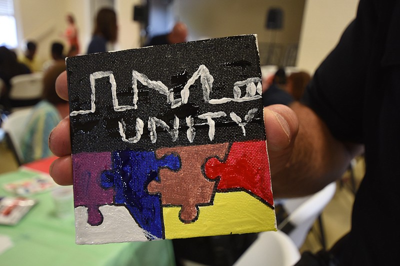Still wet with paint, this piece of mosaic tile art for the Unity Mosaic Project is held by Assistant Police Chief David Roddy on Tuesday at the Ridgedale Outreach Center. Roddy's design appears to have a skyline of downtown Chattanooga.