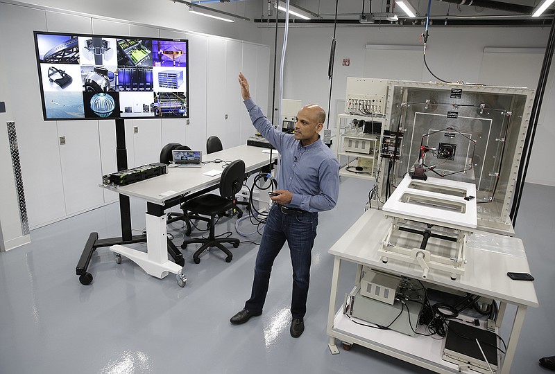 
              In this photo taken Tuesday, Aug. 2, 2016, Jay Parikh, vice president of engineering, talks about Area 404, the hardware R&D lab, during a tour at Facebook headquarters in Menlo Park, Calif. At right is a wind tunnel. (AP Photo/Eric Risberg)
            