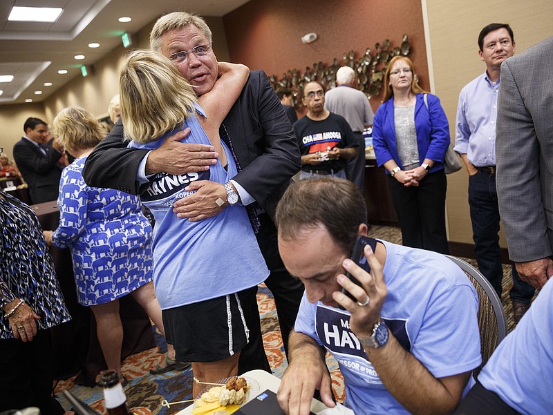 Hamilton County property assessor Marty Haynes watches election returns as he is hugged by Cinnamon Smith and Ken Smith makes phone calls to monitor results at an election party at the Holiday Inn Hotel and Suites on Thursday, Aug. 4, 2016, in Chattanooga, Tenn. Haynes defeated Democratic opponent Mark Siedlecki in the race for property assessor.
