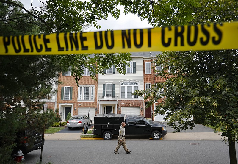 A law enforcement officer walks on the street outside the home of Nicholas Young, a Washington Metro Transit Officer, Wednesday, Aug. 3, 2016, in Fairfax, Va., Young was arrested at Metro's headquarters in Washington and charged with a single count of attempting to provided material support to a terrorist group.