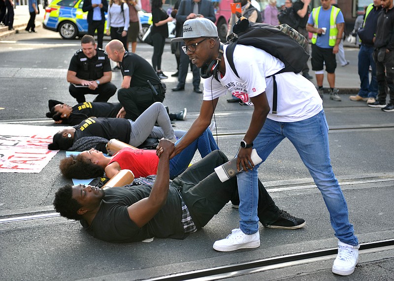 
              A man shakes hands with one of the activists as they lay on the road outside Nottingham Theatre Royal during an attempt to shut down part of the city centre tram and bus network in Nottingham, England Friday Aug. 5, 2016 to protest for social justice movement Black Lives Matter. Activists affiliated with the U.S.-based group Black Lives Matter have blocked a road leading to Heathrow Airport, and Nottinghamand city centre along with protests  in other British cities (Edward Smith/PA via AP)
            