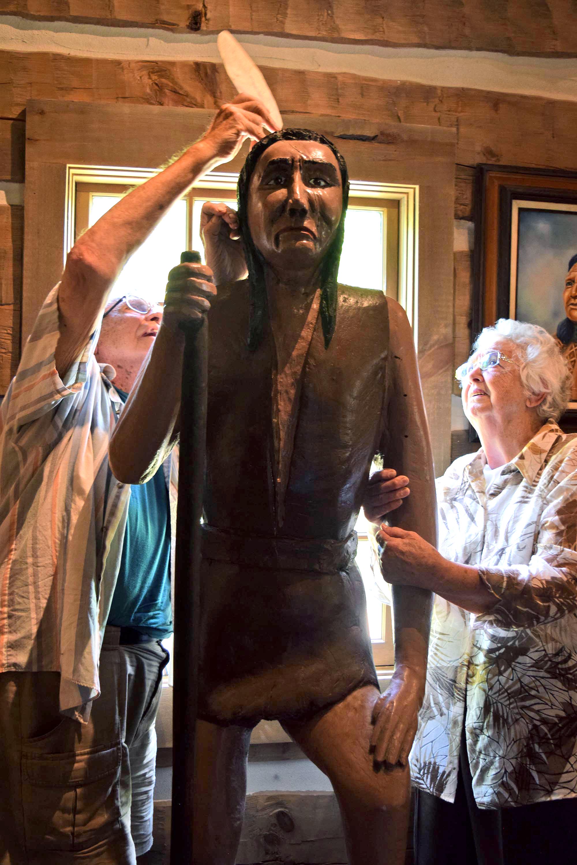 Shirley Hoskins, right, watches her husband, Ray, fix a feather to the top of a sculpture of Cherokee interpreter John Spears on Thursday. The Hoskins donated the sculpture, carved by Ray in the early-1990s, to the Cherokee Removal Memorial Park. Shirley Hoskins is the great-great-great-great granddaughter of Spears.