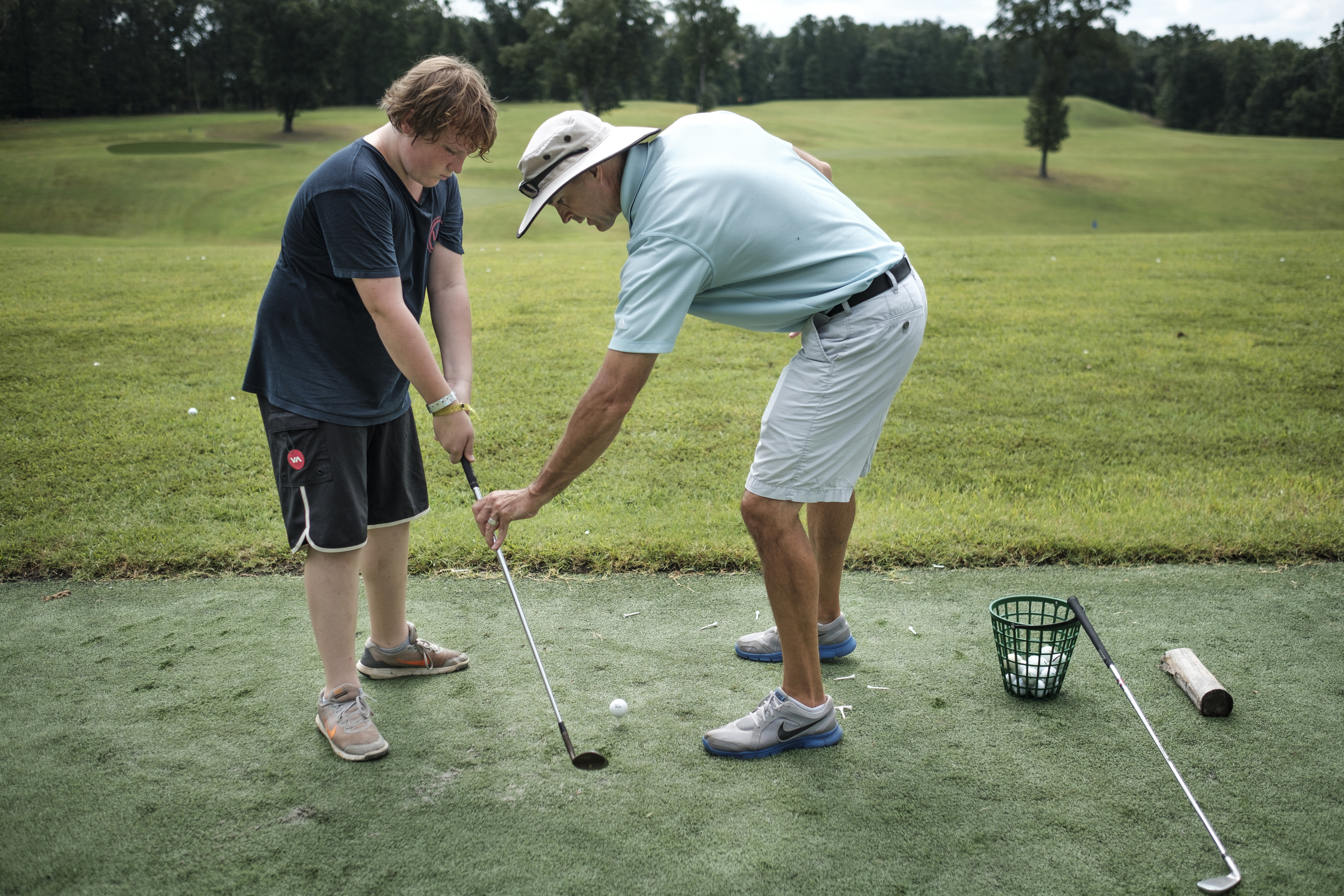 Golf pro Mark Parry helps Ethan Cook with his golf swing at the Kids Across America camp Wednesday, July 27, 2016, near Branson, Mo. Cook is one of many inner-city youths from Chattanooga brought to the camp by Chattanooga police officer Danny Jones.
