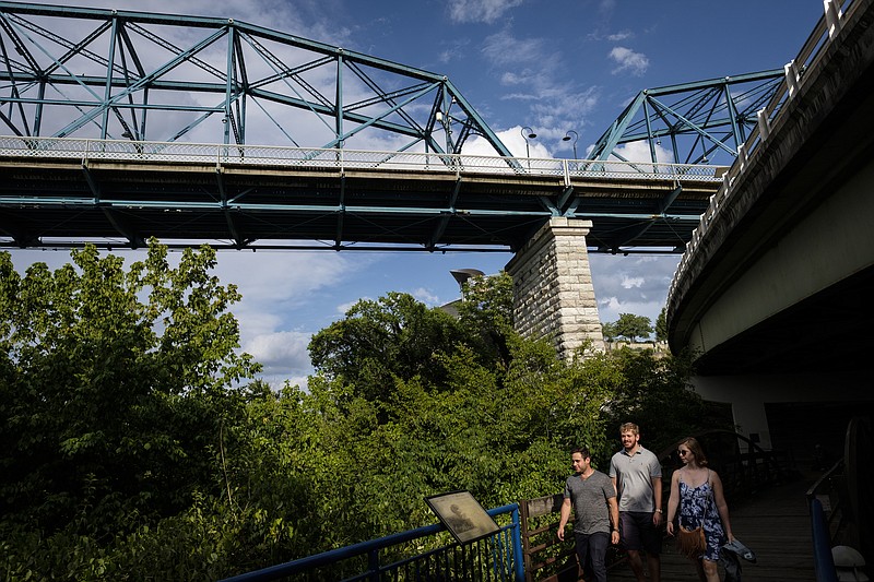 Joshua Goldberg, Alex Rubin, and Haleigh Cooper, from left, walk on the Tennessee Riverwalk beneath the Walnut Street Bridge on Wednesday, July 6, 2016, in Chattanooga, Tenn. $9 million are planned for rehabilitation of the bridge.
