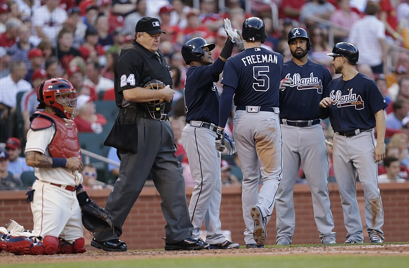 Atlanta Braves' Freddie Freeman (5) celebrates with teammates after hitting a three-run home run as home plate umpire Jerry Layne (24) and St. Louis Cardinals catcher Yadier Molina look on in the third inning of a baseball game Saturday, Aug. 6, 2016, in St. Louis.