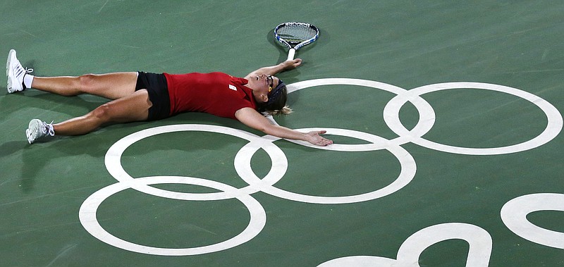 
              CORRECTS COUNTRY FROM BELARUS TO BELGIUM - Kirsten Flipkens, of Belgium, collapses on the Olympic rings at center court after defeating Venus Williams, of the United States, in three sets at the 2016 Summer Olympics in Rio de Janeiro, Brazil, Saturday, Aug. 6, 2016. (AP Photo/Charles Krupa)
            
