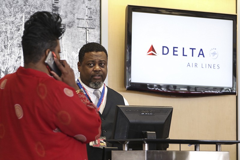Staff Photo by Dan Henry / The Chattanooga Times Free Press- 8/8/16. Delta associate Sheldon Posey informs Sheila Simpson that there is a delay in one of her Job Corp student's flight to Lousiville, KY, while at the Chattanooga Airport ticking counter on Monday, August 8, 2016. Delta Air Lines flights were delayed and canceled following a global computer system outage early Monday morning. 