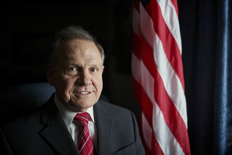 
              FILE - In this Feb. 17, 2015, file photo, Alabama Chief Justice Roy Moore poses in front the the American flag in Montgomery, Ala.  Moore has been suspended from office after the Judicial Inquiry Commission accused him of violating the canons of judicial ethics with his actions during the fight over same-sex marriage. Moore will attend a hearing Monday, Aug. 8, 2016 that will determine the course of the judicial ethics case against the suspended Alabama Chief Justice. (AP Photo/Brynn Anderson, File)
            