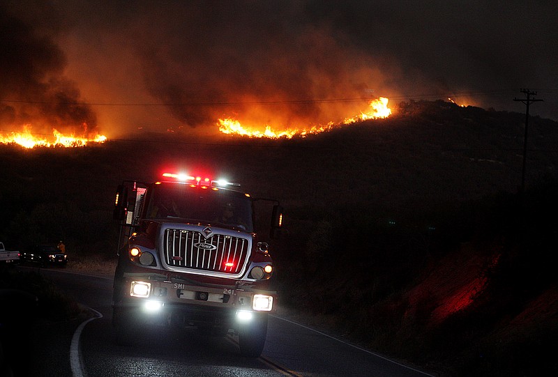 
              A fire engine drives away from flames on the ridge, east of Silverwood Lake in Crestline, Calif., Sunday, Aug 7, 2016. (Terry Peirson/The Press-Enterprise via AP)
            